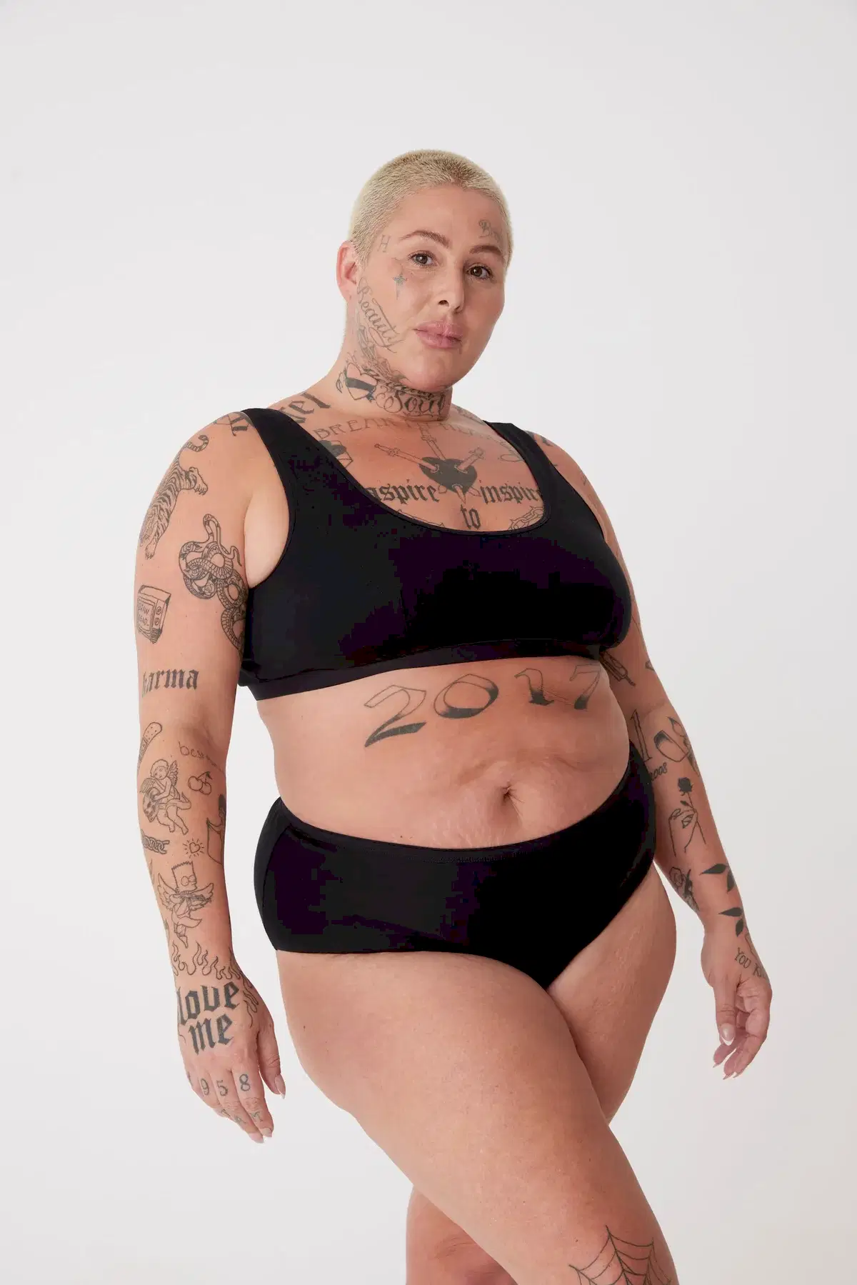 tattooed, plus size, white female in black high rise brief paired with black jersey bralette 