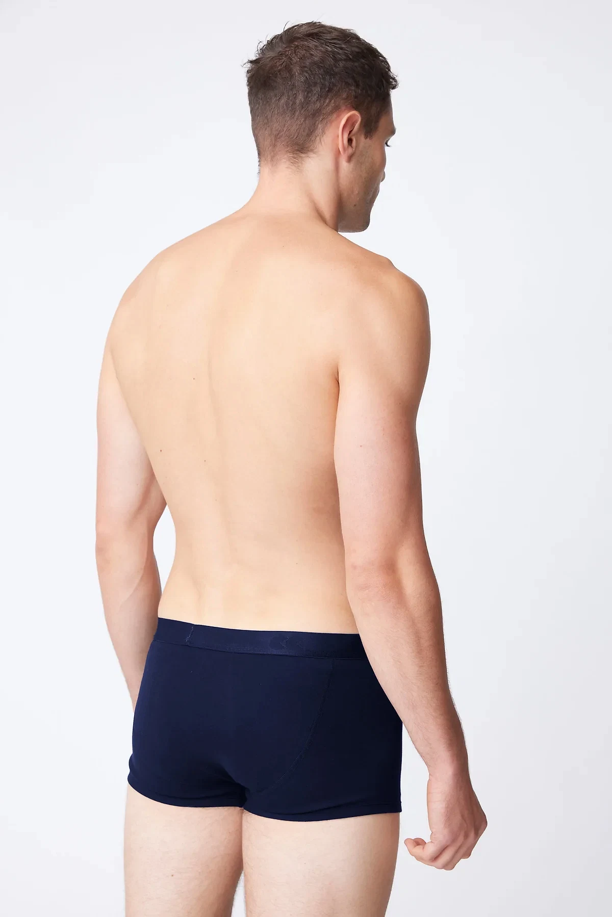 White male wearing navy trunks 